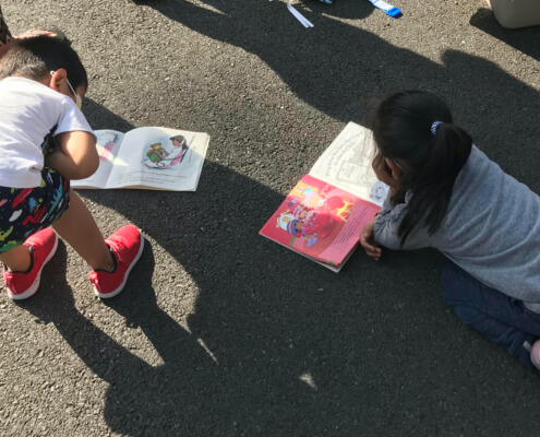 Two children reading at UIDN’s weekly market.