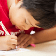 Photo of child in red t-shirt writing.