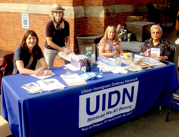 Volunteers sitting at a table with a blue tablecloth smiling